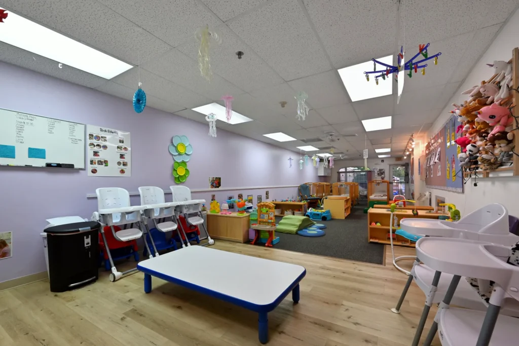 Toddler room with high chairs, a low table and play areas at The Learning Tree Center in Lake Zurich, IL